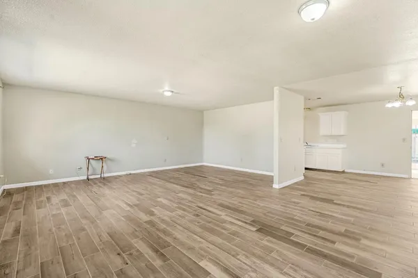 a view of an empty room with wooden floor and window