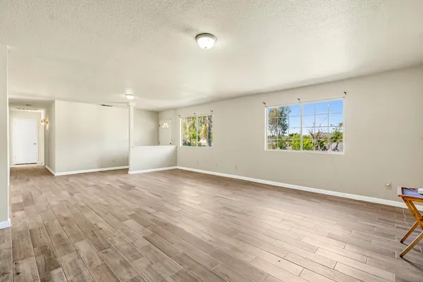 a view of an empty room with a window and wooden floor