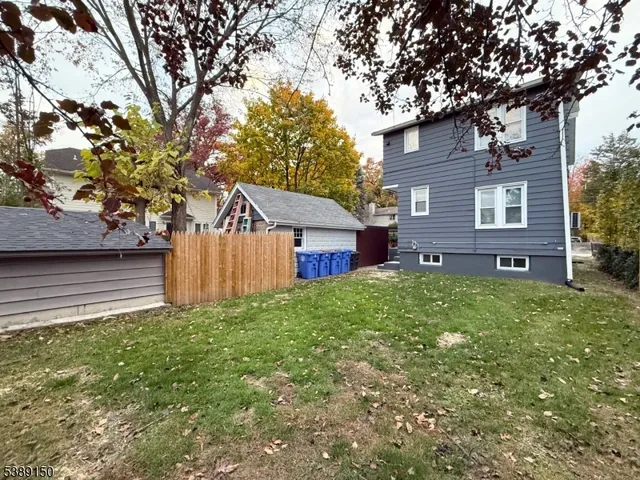 a view of a house with a yard and a large tree