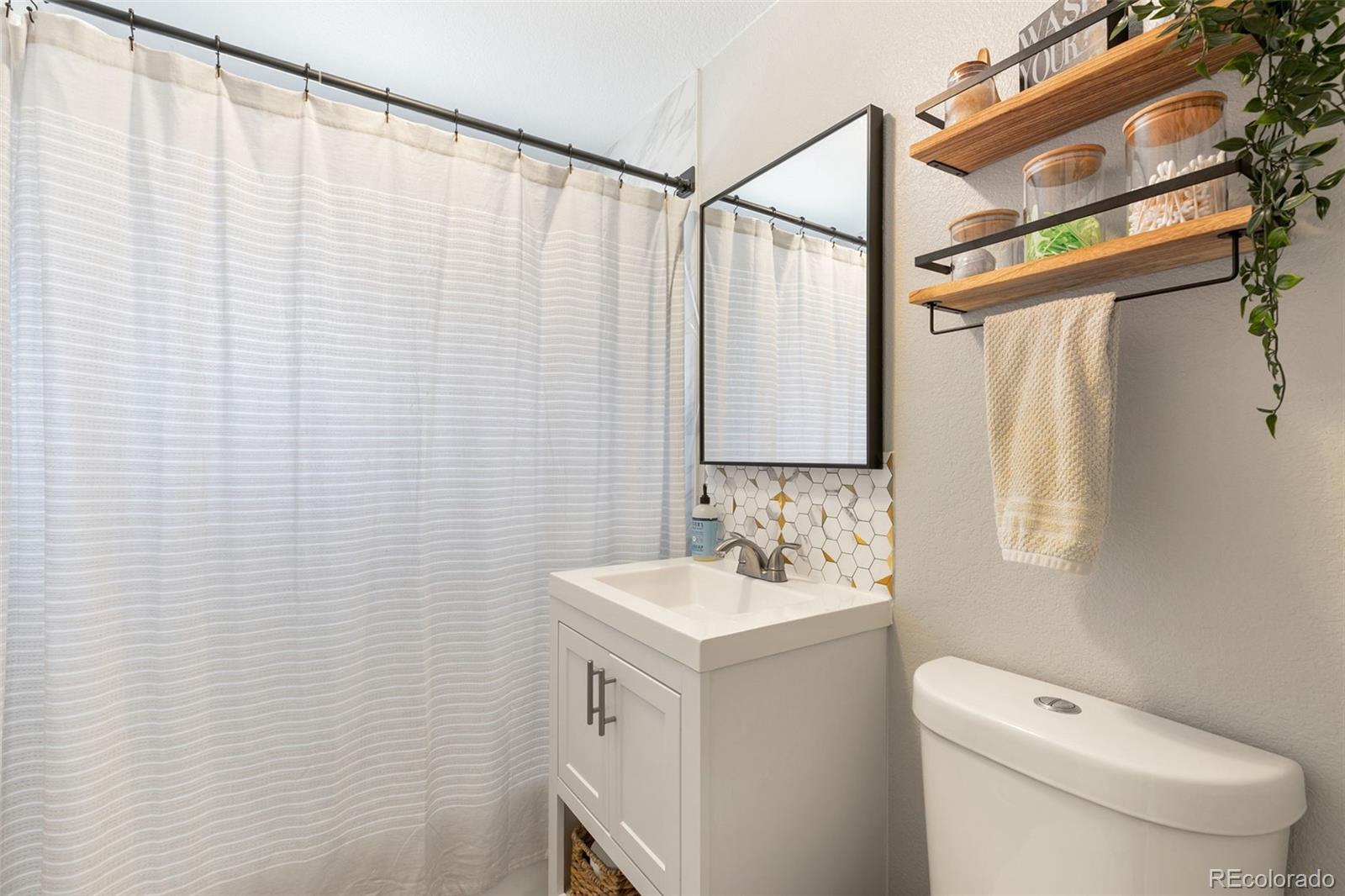 2023 Winston Road Colorado Springs, CO 80909 - Photo 13 of 39 a bathroom with a sink a toilet and shower curtain