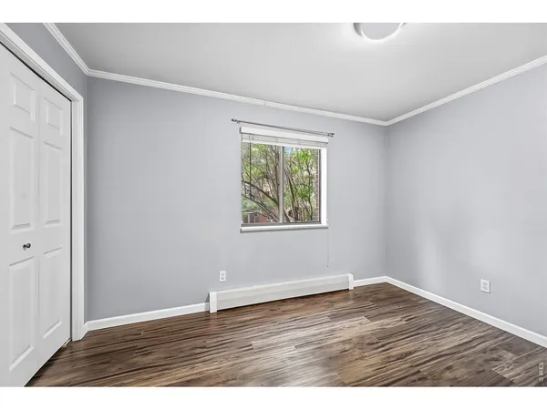 an empty room with wooden floor and window