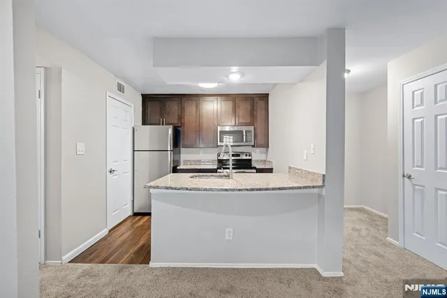a view of kitchen with stainless steel appliances granite countertop cabinets and a refrigerator