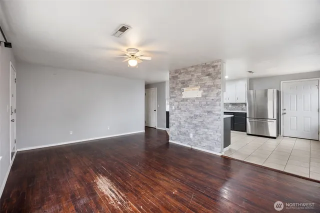 a view of empty room with wooden floor and ceiling fan