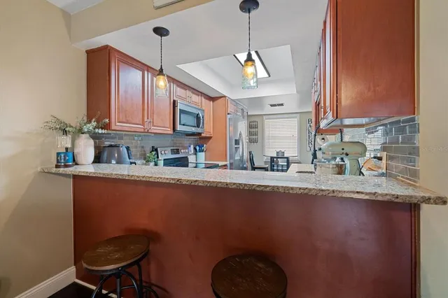a kitchen with stainless steel appliances granite countertop a sink a microwave cabinets and a dining table