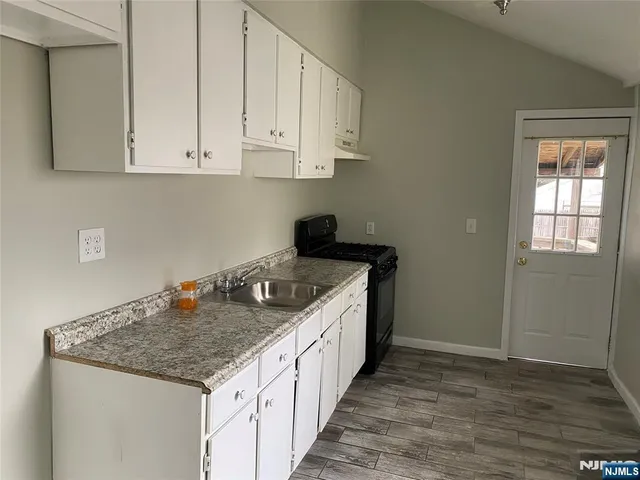 a kitchen with granite countertop white cabinets and a stove