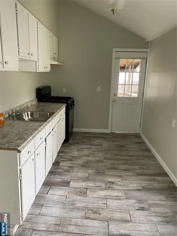 a kitchen with granite countertop white cabinets and sink
