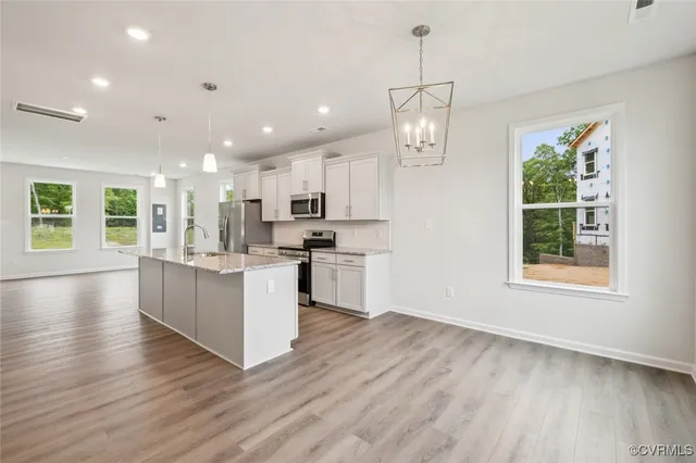 a view of kitchen with kitchen island wooden floor center island and stainless steel appliances