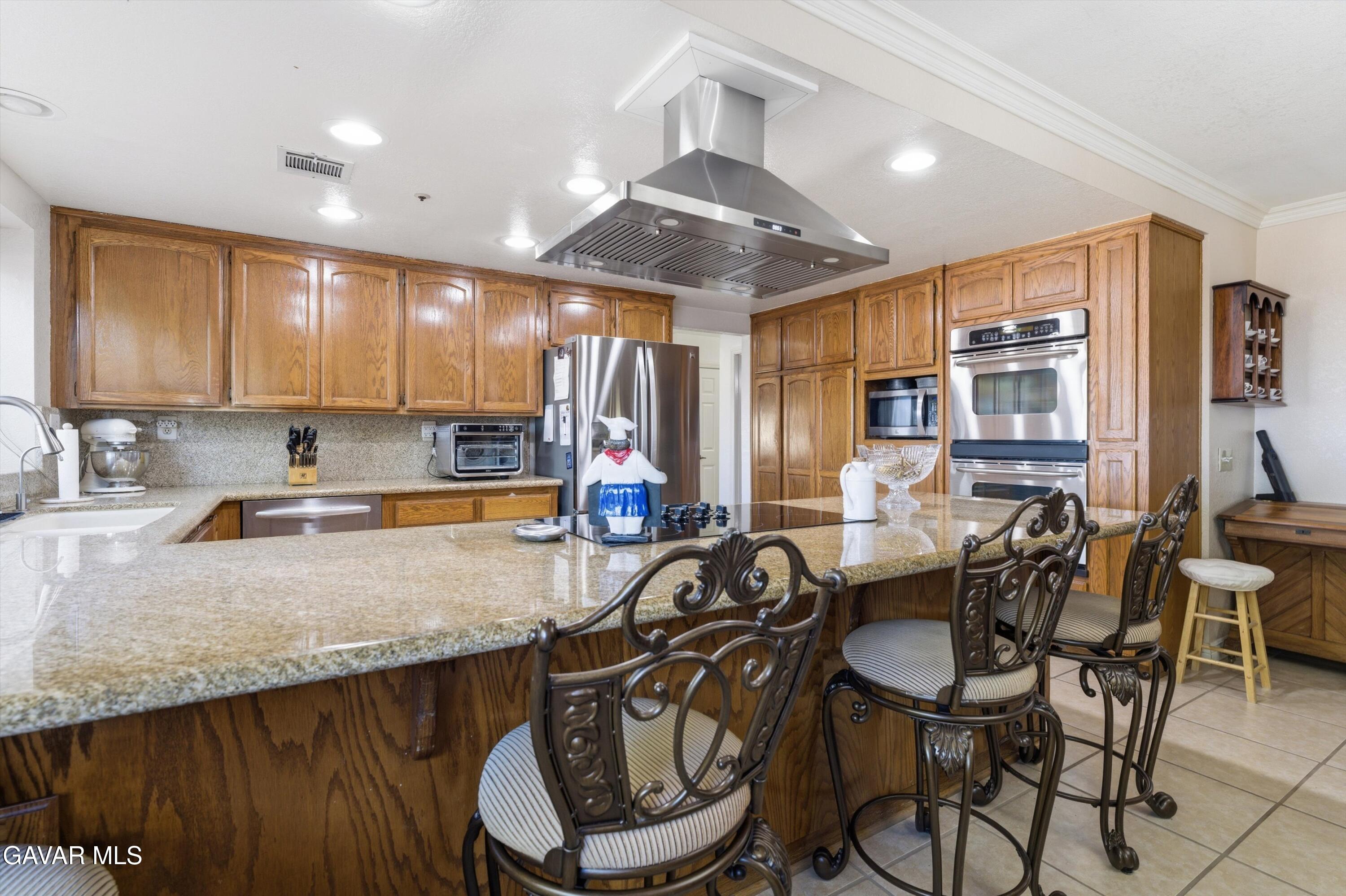 5801 Hacienda Ranch Road Palmdale, CA 93551 - Photo 17 of 69 a kitchen with granite countertop a table chairs stove and refrigerator