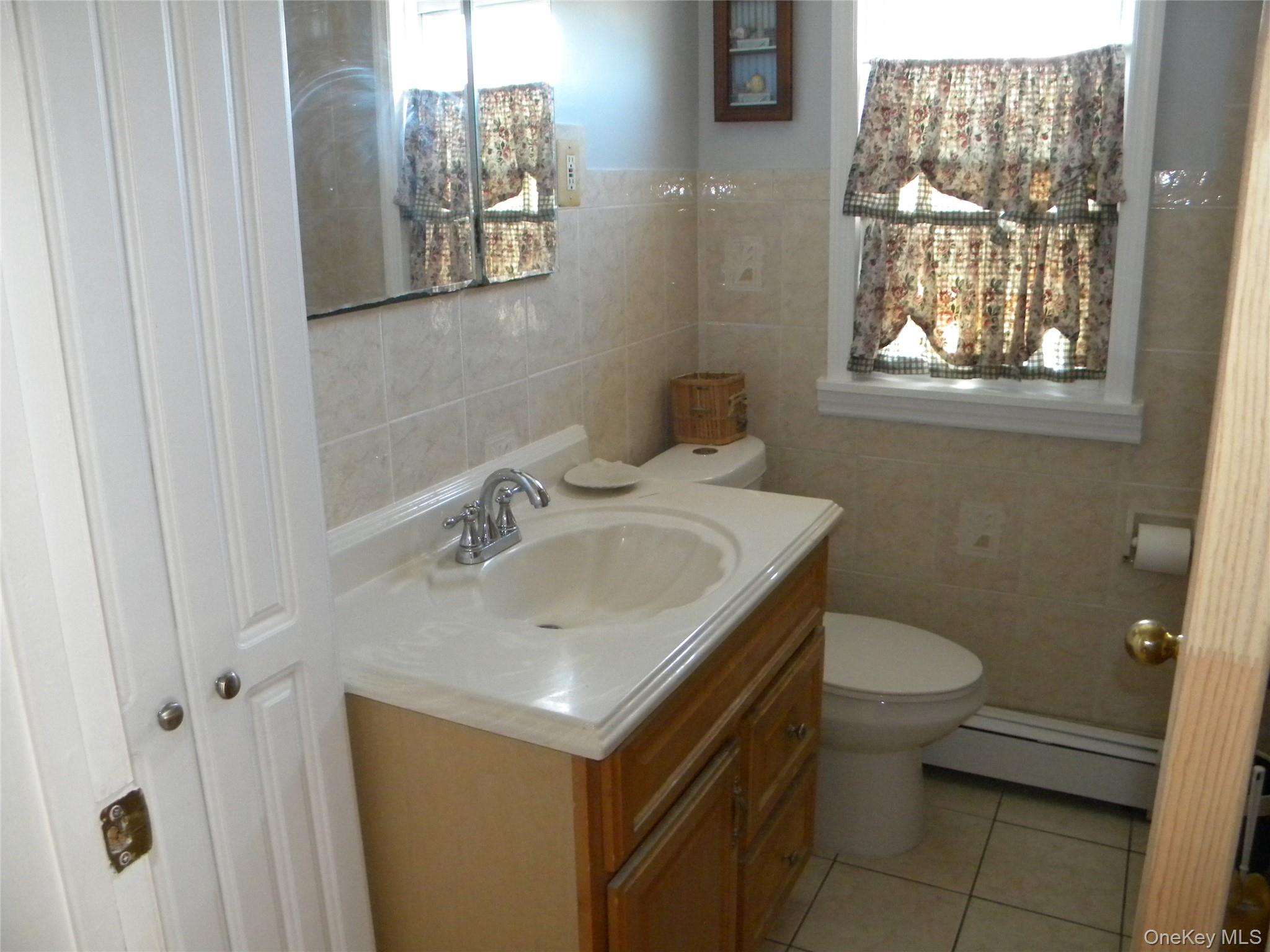 241-26 86th Road Queens, NY 11426 - Photo 16 of 38 a bathroom with a sink toilet and a window