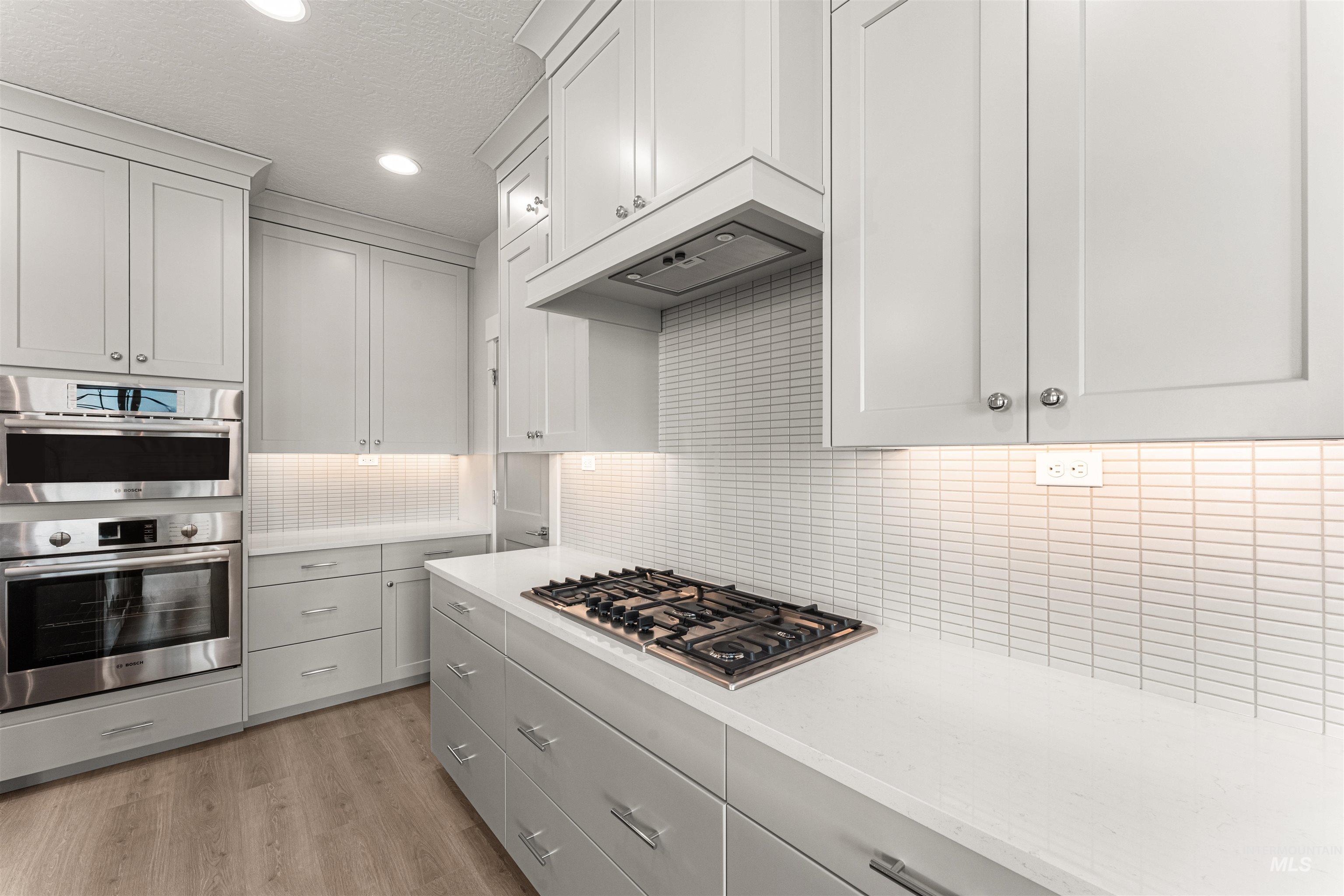8080 Tandy Cv Street Middleton, ID 83644 - Photo 10 of 35 Kitchen featuring stainless steel appliances, light wood-style floors, decorative backsplash, recessed lighting, and light stone counters