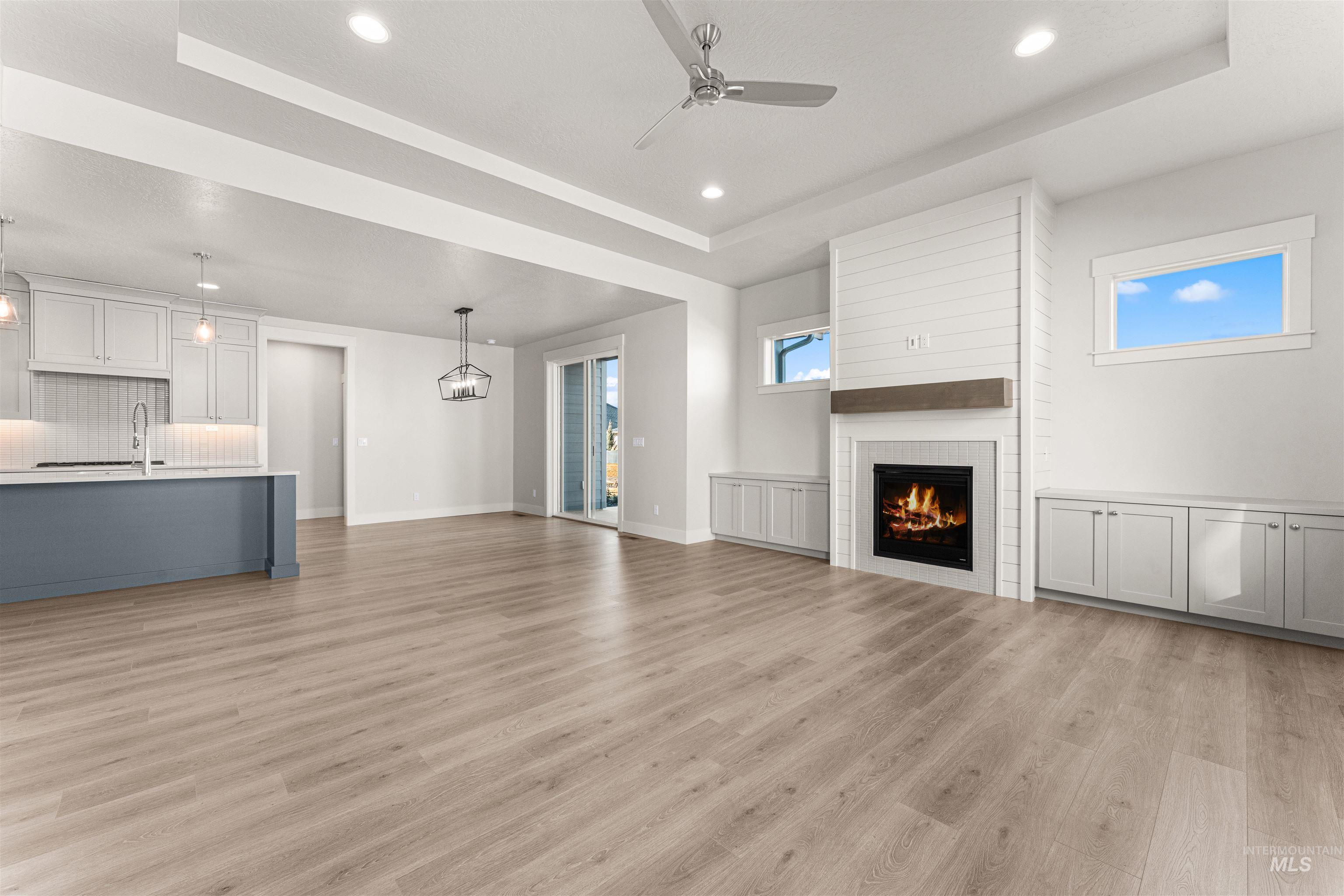 8080 Tandy Cv Street Middleton, ID 83644 - Photo 5 of 35 Unfurnished living room with a tray ceiling, a ceiling fan, recessed lighting, a tile fireplace, and light wood finished floors