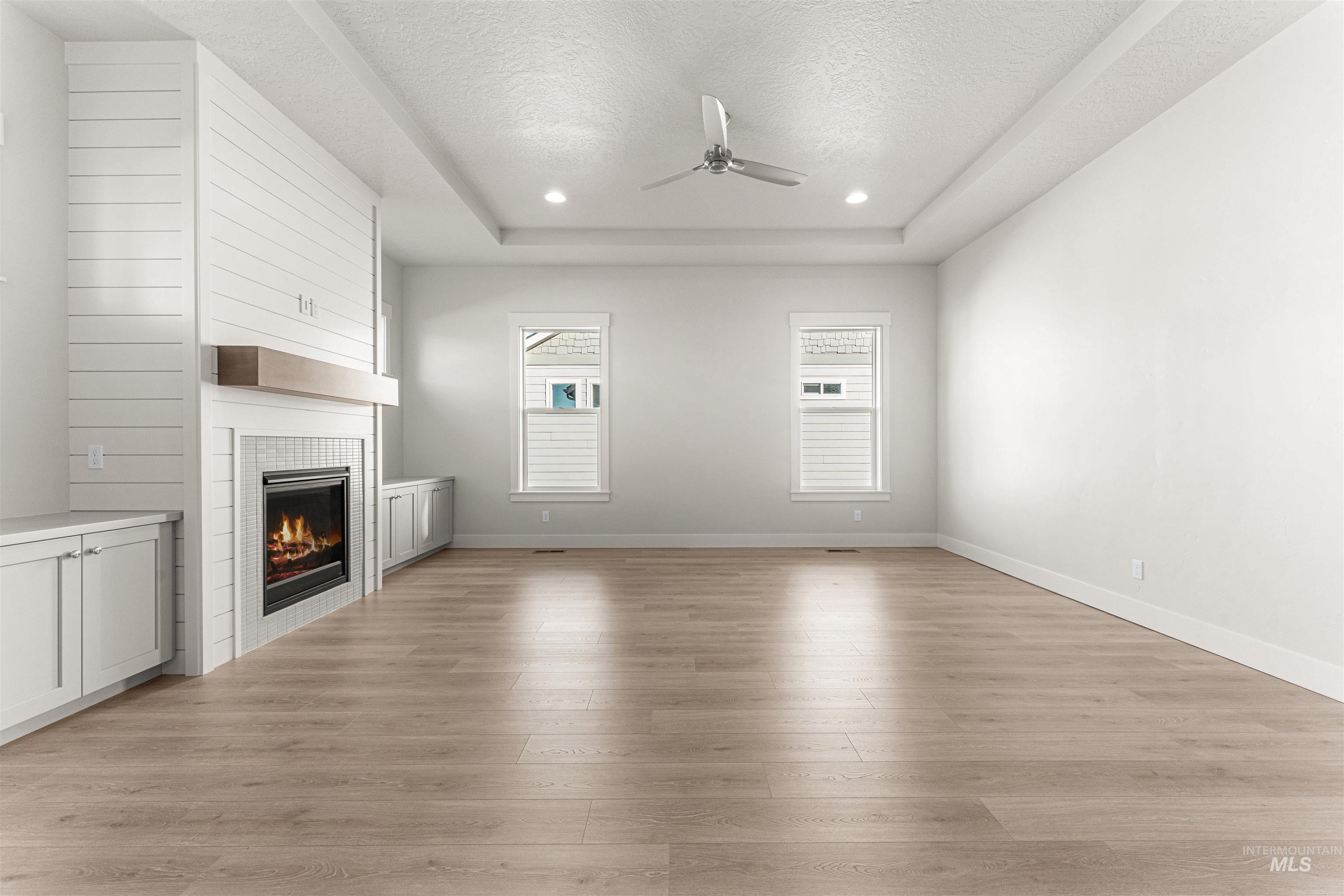 8080 Tandy Cv Street Middleton, ID 83644 - Photo 6 of 35 Unfurnished living room with a ceiling fan, light wood-type flooring, a tiled fireplace, a textured ceiling, and recessed lighting
