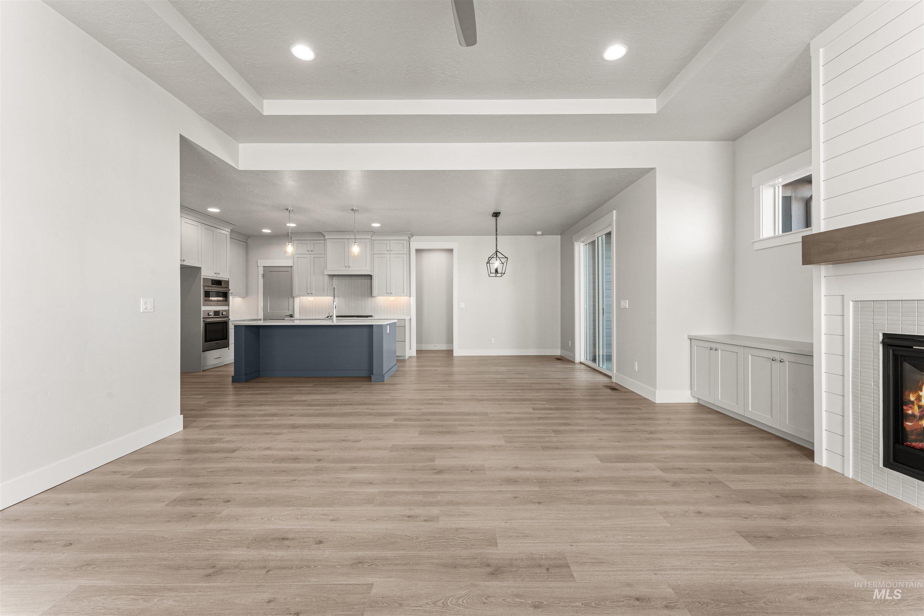 8080 Tandy Cv Street Middleton, ID 83644 - Photo 34 of 35 Kitchen featuring open floor plan, a tile fireplace, pendant lighting, a kitchen island with sink, and light countertops