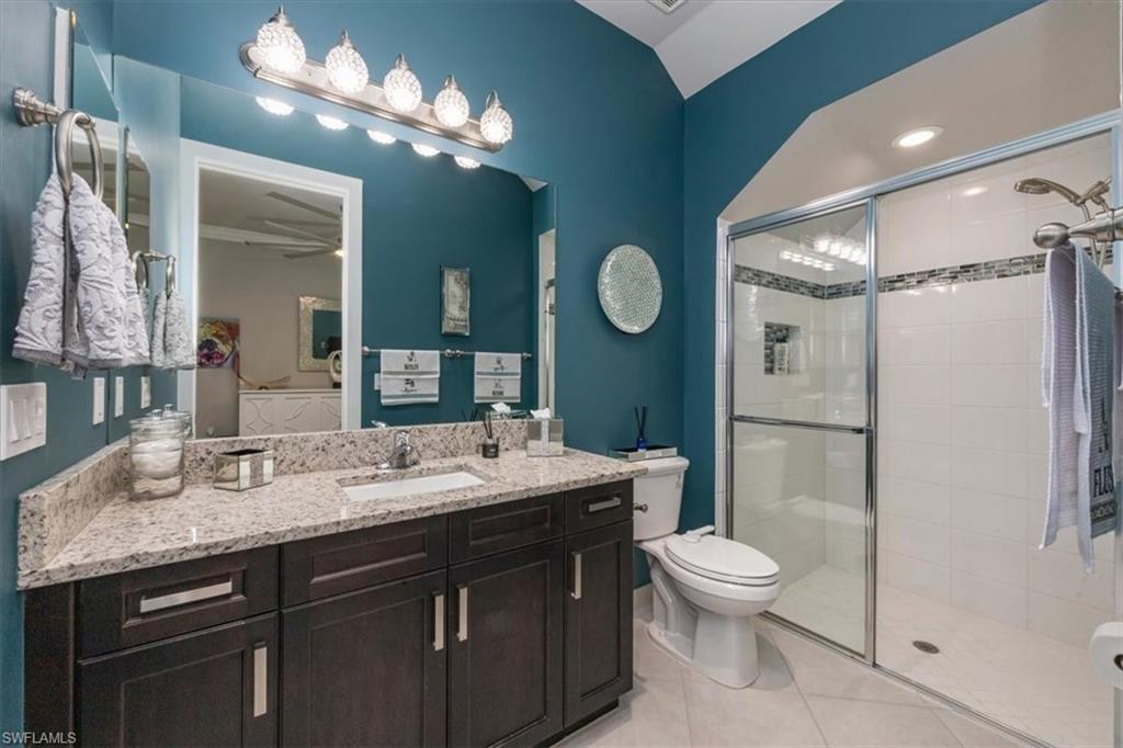 4172 Crescent Court Naples, FL 34119 - Photo 14 of 46 a bathroom with a granite countertop sink toilet a mirror a vanity and shower