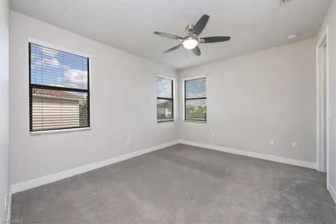 an empty room with windows and fan
