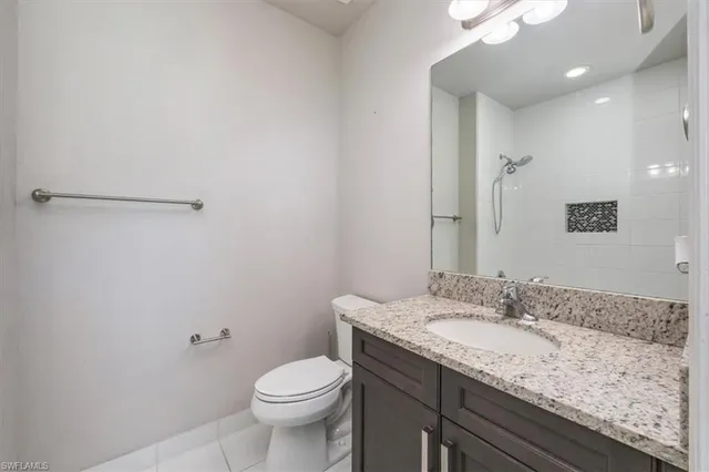 a bathroom with a granite countertop sink a toilet and a mirror
