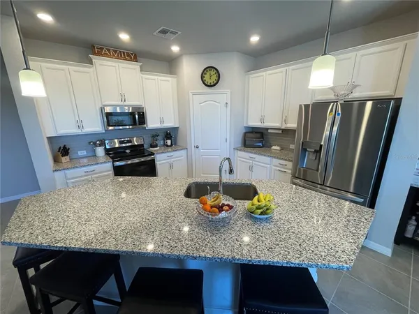 a kitchen with stainless steel appliances granite countertop a sink refrigerator and microwave