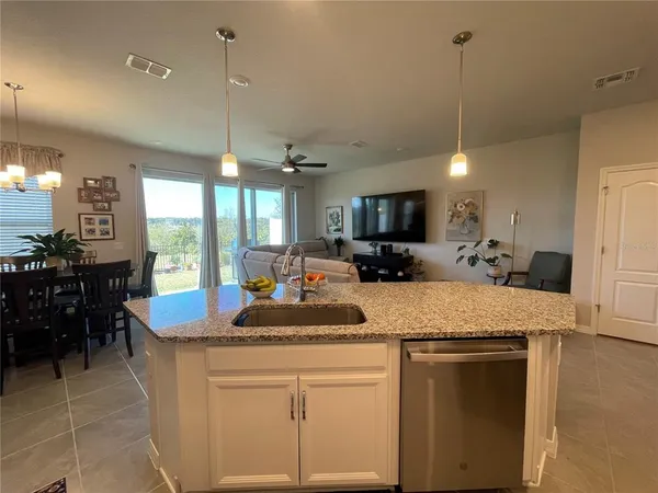 a kitchen with kitchen island granite countertop a stove a sink a oven a dining table and chairs with wooden floor