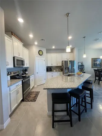 a kitchen with stainless steel appliances kitchen island granite countertop a table chairs sink and cabinets