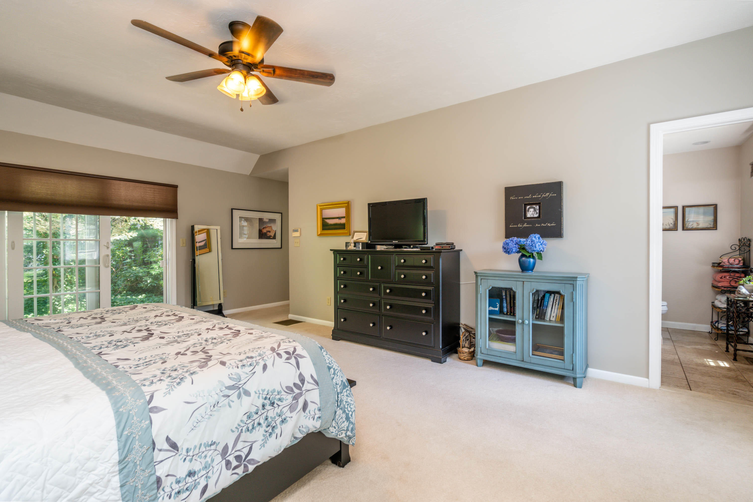 96 Breakwater Road Brewster, MA 02631 - Photo 9 of 16 a spacious bedroom with a bed a dresser and a chandelier