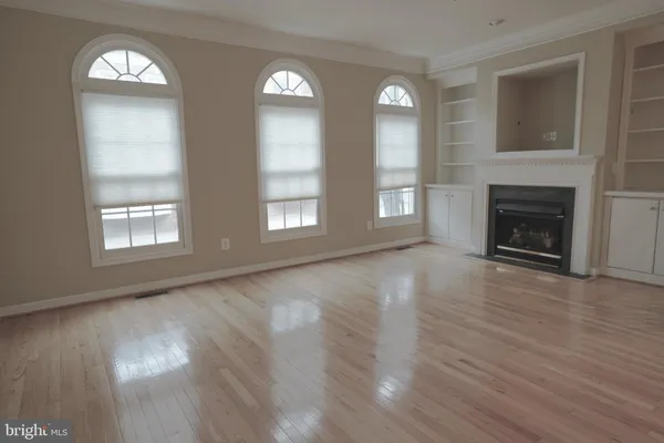 an empty room with wooden floor fireplace and windows