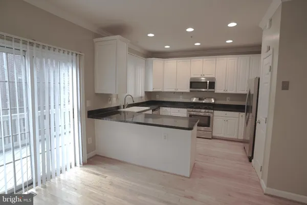 a kitchen with kitchen island granite countertop a sink cabinets and stainless steel appliances
