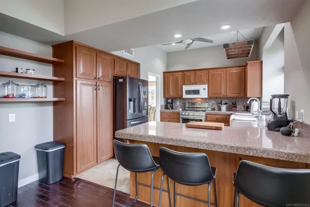 a kitchen with stainless steel appliances granite countertop a stove top oven a refrigerator a sink and a dining table with wooden floor