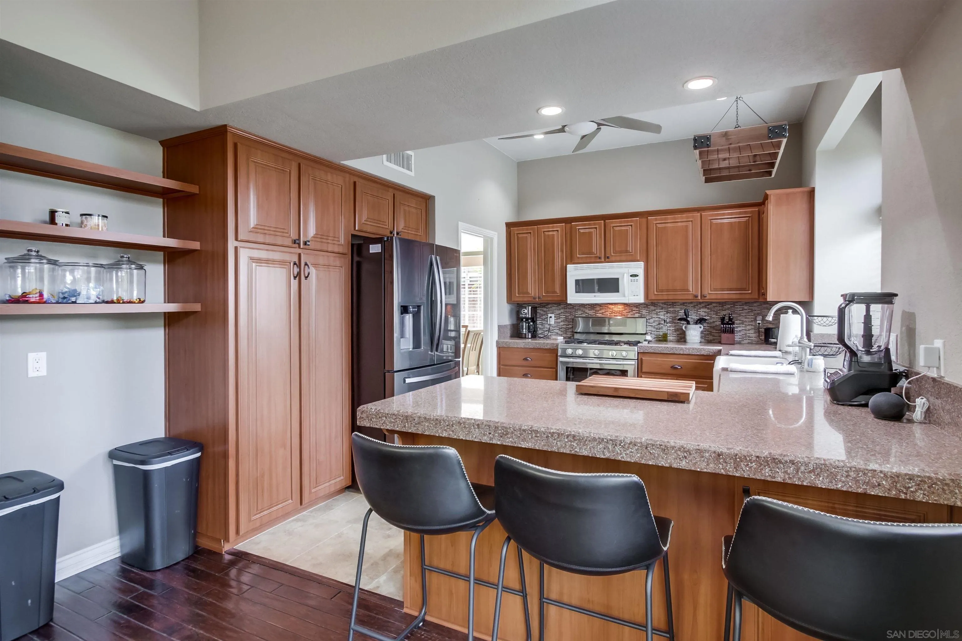 930 Gardena Road Encinitas, CA 92024 - Photo 9 of 27 a kitchen with stainless steel appliances granite countertop a stove top oven a refrigerator a sink and a dining table with wooden floor