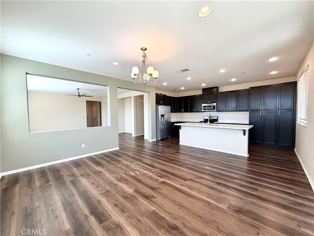 a view of kitchen with kitchen island wooden floor center island and stainless steel appliances