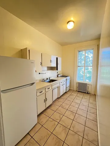 a kitchen with a refrigerator a stove top oven and white cabinets