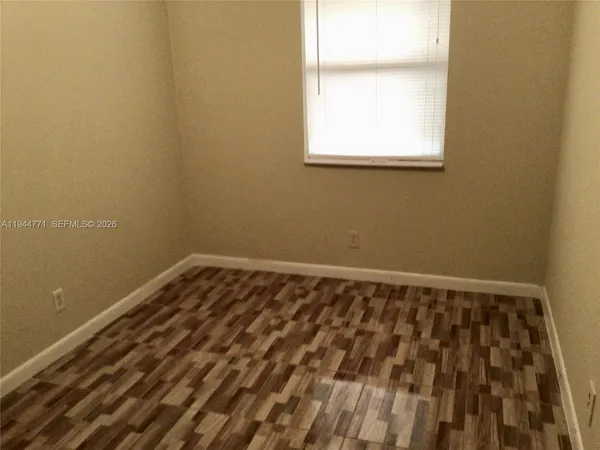 a view of a room with wooden floor and a window