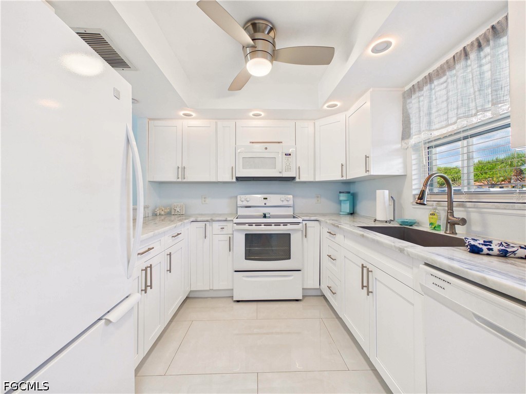 300 Valley Stream Drive, Unit 3D Naples, FL 34113 - Photo 8 of 21 a white kitchen with granite countertop a stove top oven a sink a window and white cabinets