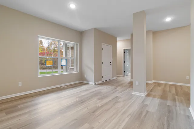 a view of an empty room with window and wooden floor
