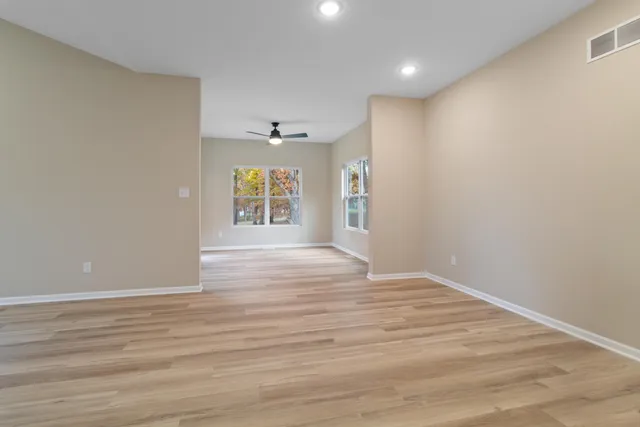a view of an empty room with wooden floor and a window