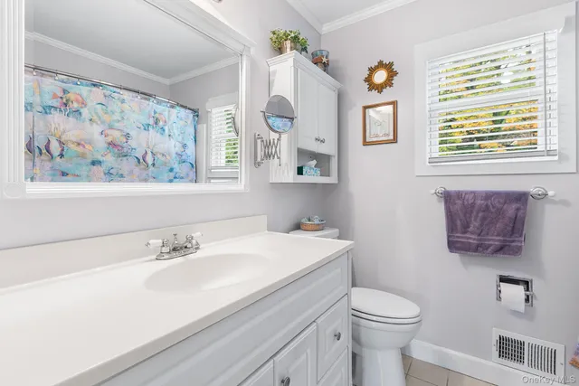 a bathroom with a sink a mirror a toilet and a window