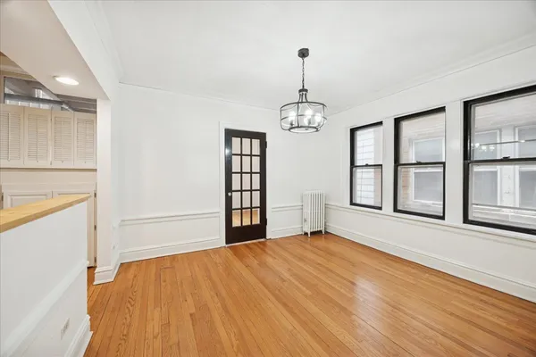 a view of an empty room with window and wooden floor