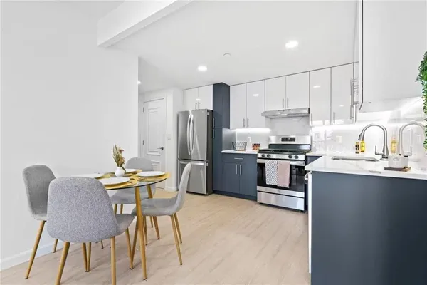 a kitchen with stainless steel appliances kitchen island granite countertop a table chairs microwave and sink