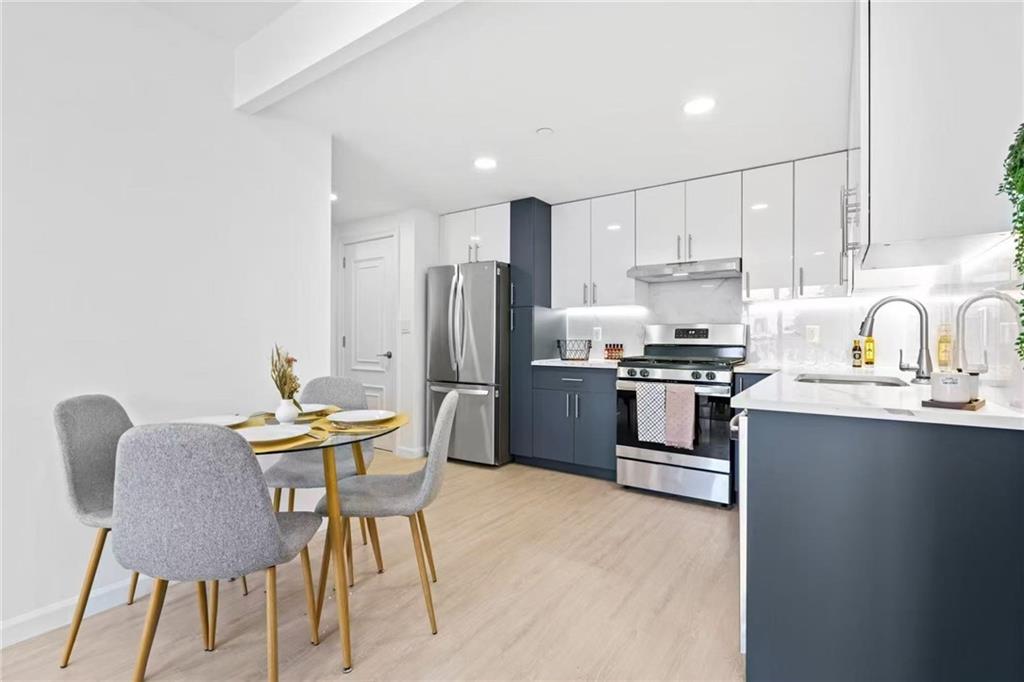 42-80 Main Street, Unit 5E Queens, NY 11355 - Photo 9 of 11 a kitchen with stainless steel appliances kitchen island granite countertop a table chairs microwave and sink