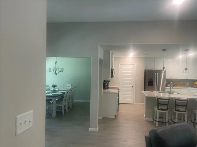 a kitchen with kitchen island a dining table chairs and stainless steel appliances