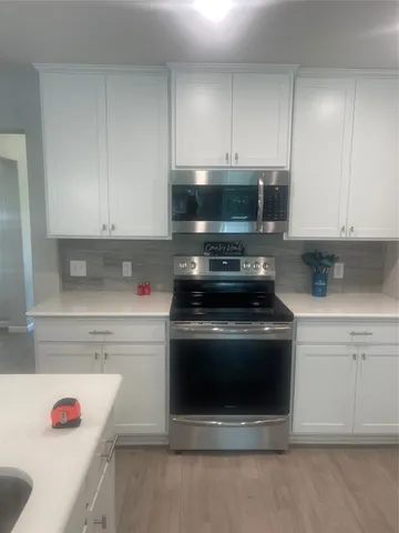 a kitchen with a stove and white cabinets