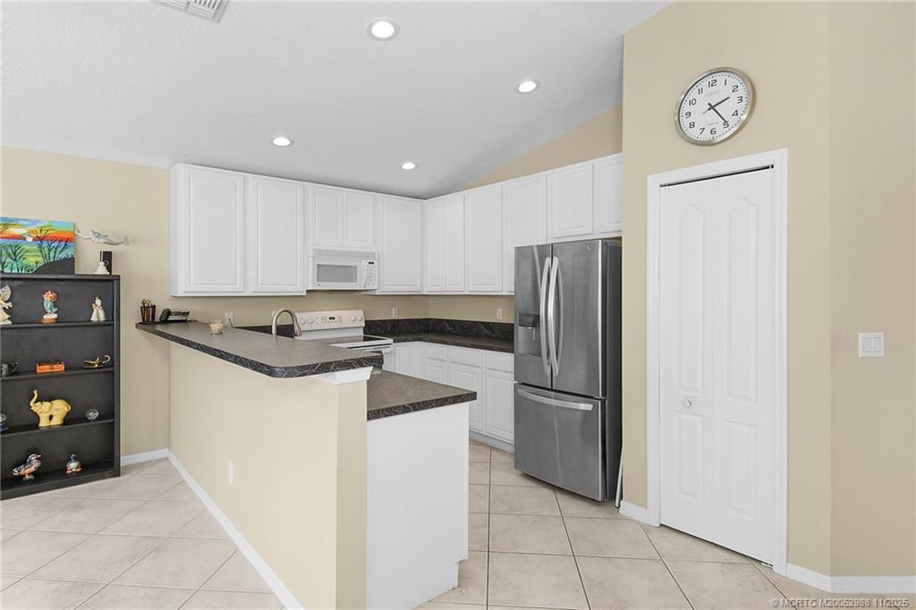 486 Northwest Sunflower Place Stuart, FL 34994 - Photo 14 of 42 a kitchen with granite countertop a refrigerator and a stove top oven