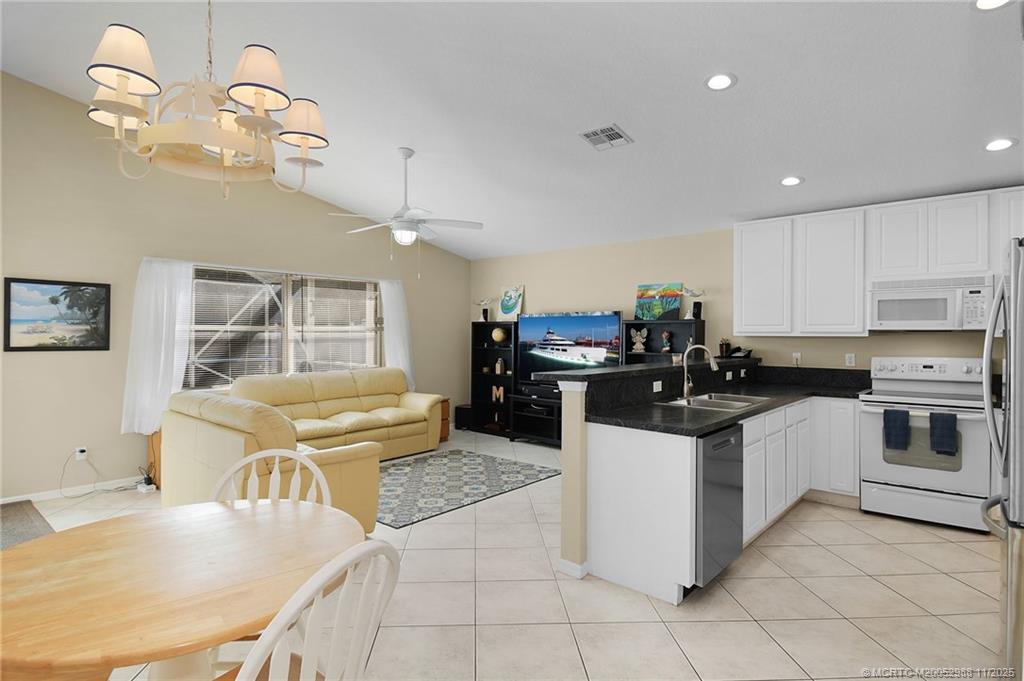 486 Northwest Sunflower Place Stuart, FL 34994 - Photo 15 of 42 a kitchen with stainless steel appliances granite countertop a sink dishwasher a stove a refrigerator and a dining table with wooden floor