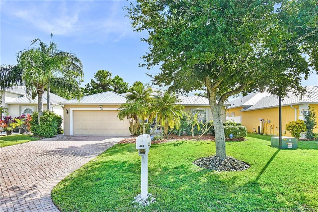 486 Northwest Sunflower Place Stuart, FL 34994 - Photo 3 of 42 a front view of a house with a yard and palm trees