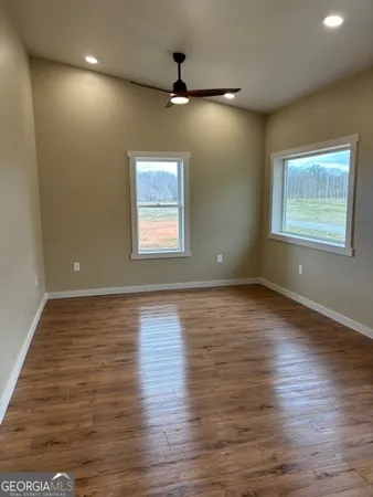 an empty room with wooden floor and windows