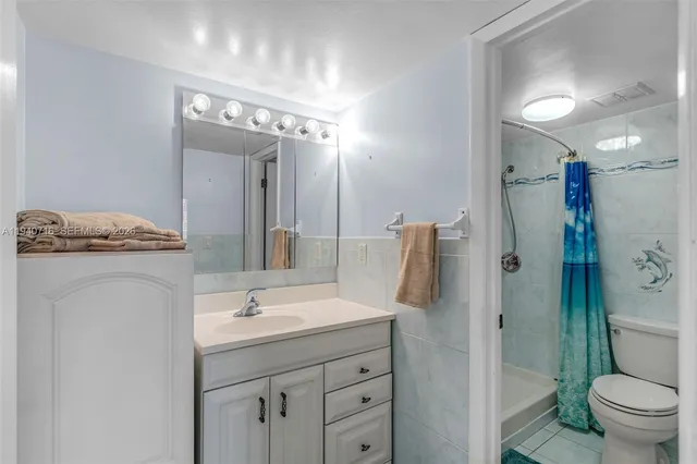 a bathroom with a granite countertop sink a toilet a mirror and shower
