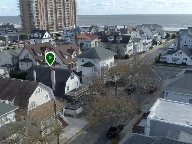 a view of a white house with a large space and a car parked beside it