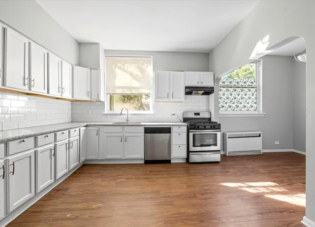 a kitchen with granite countertop a sink cabinets and stainless steel appliances