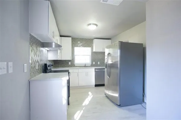 a kitchen with a refrigerator sink and cabinets