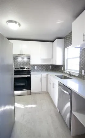 a kitchen with granite countertop white cabinets and stainless steel appliances