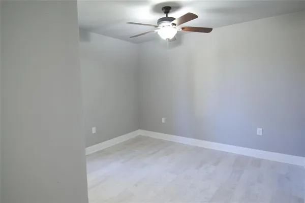 an empty room with a fan & a window